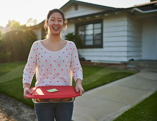 A woman standing in front of a house, offering a donation
